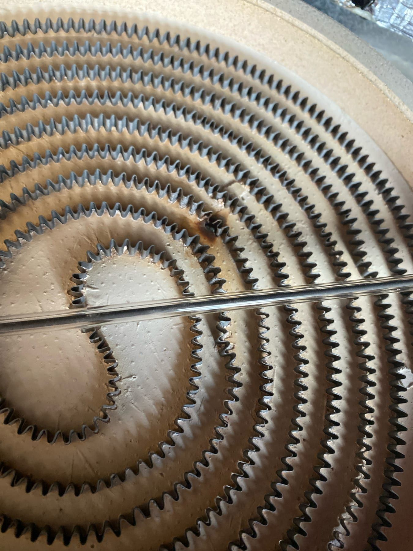 Cooktop repair in Toronto — close-up of a ribbon heating element on its ceramic base with a dark burnt patch and a break in the ribbon