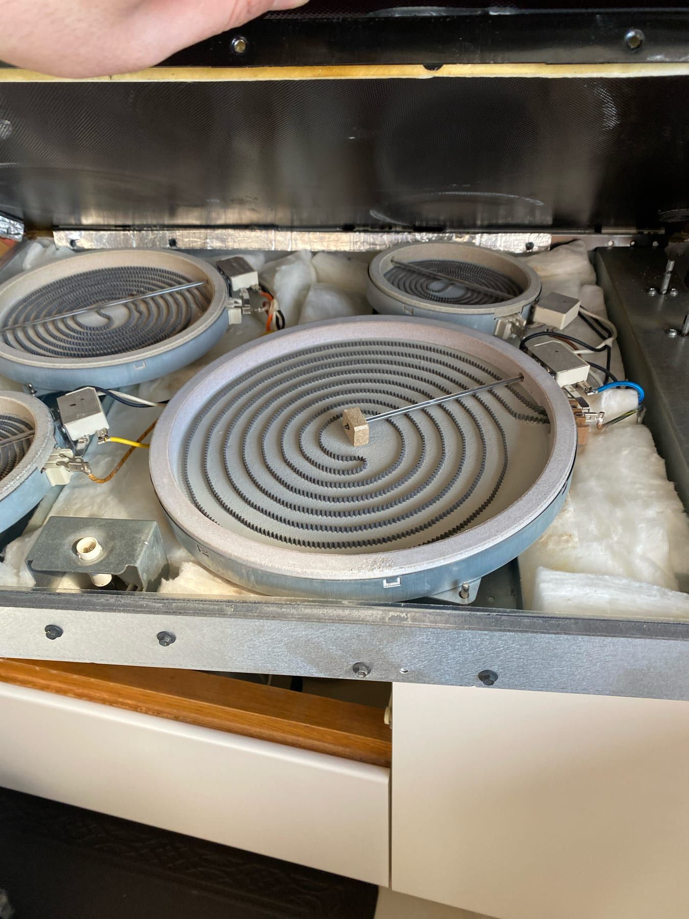 Cooktop repair in Toronto — raised glass panel with four ribbon heating elements in mineral wool, ceramic limiters and colour-coded wiring underneath