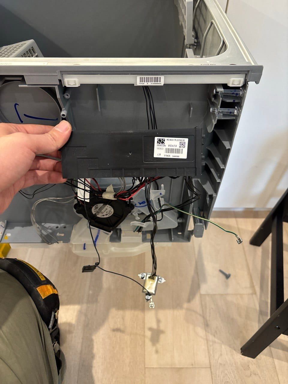 Dishwasher repair in Toronto — control module lifted out of the opened dishwasher door, with the drying fan and wiring below