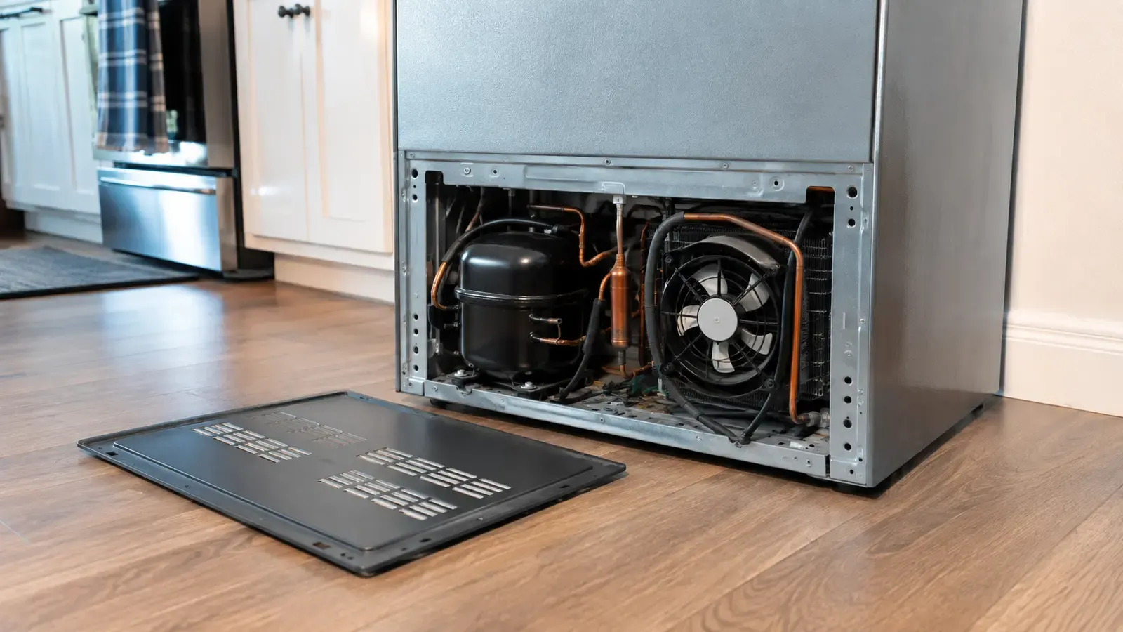 Technician listening to a running refrigerator to identify the source of a noise