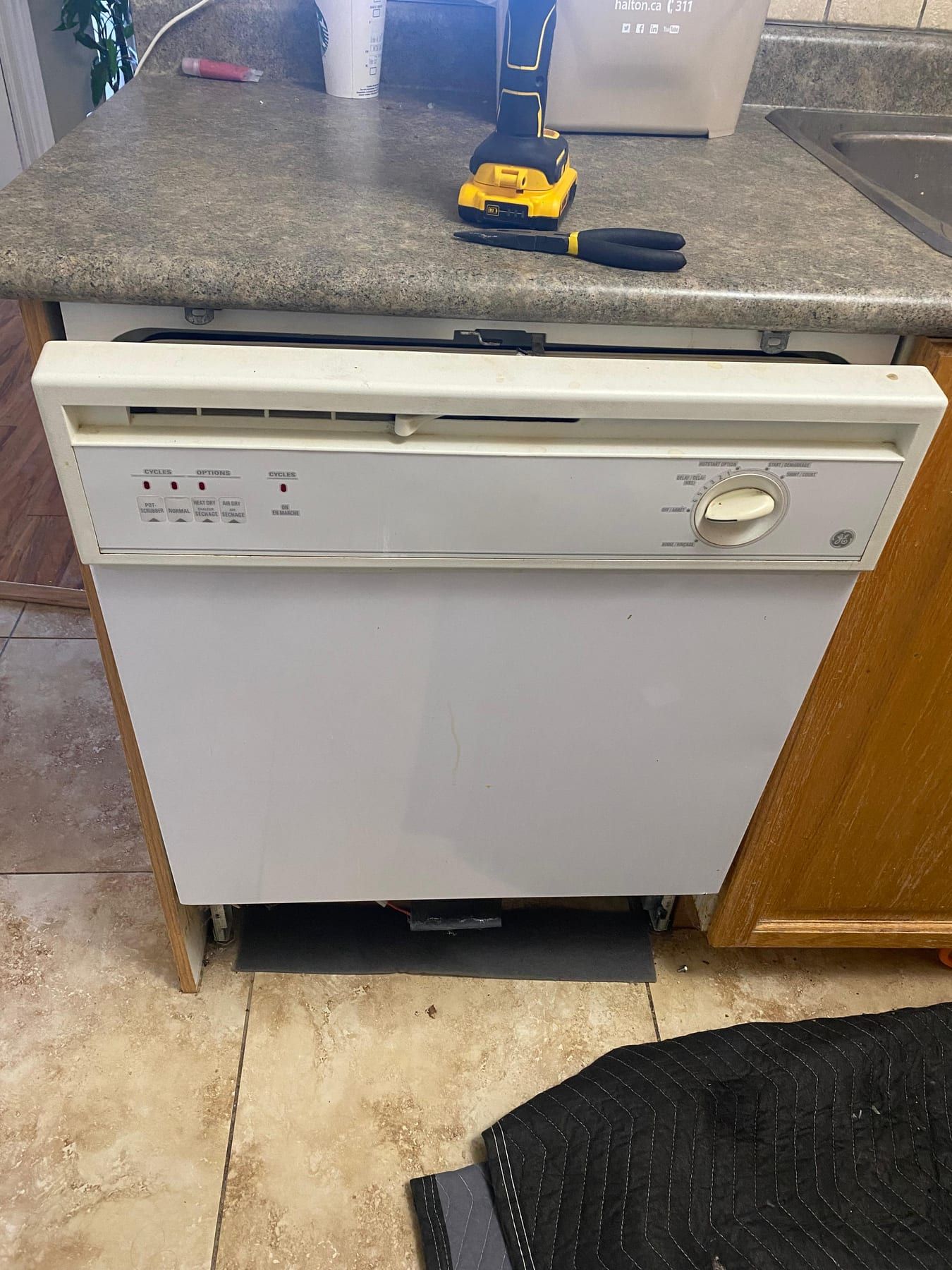 GE dishwasher repair in Toronto — built-in dishwasher under the counter with the lower kick plate removed and tools on the countertop