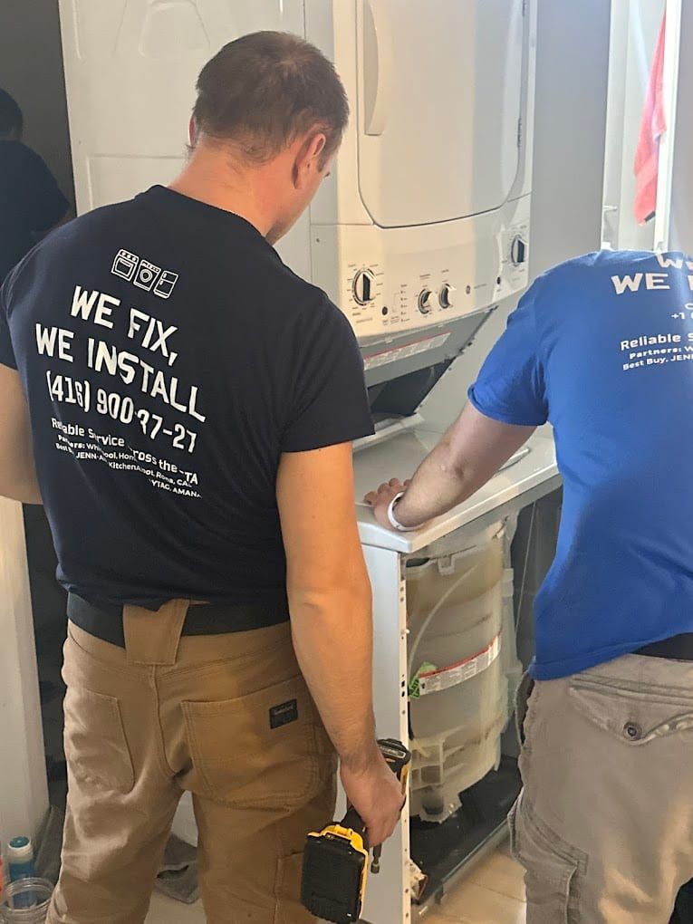Washer repair in Toronto — stacked washer and dryer with the lower front panel removed, exposing the tub and the drive components